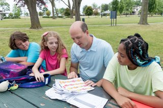 Kevin Hertel helping students with homework at a picnic table outdoors